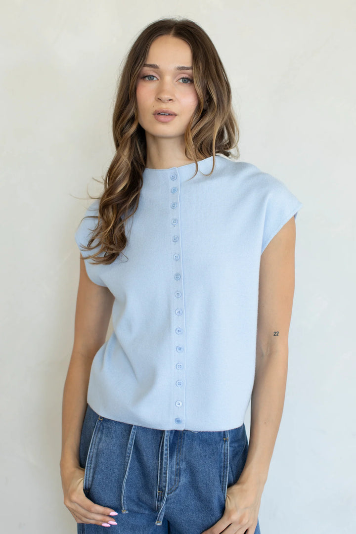 Woman wearing a light blue blouse and blue jeans against a plain background