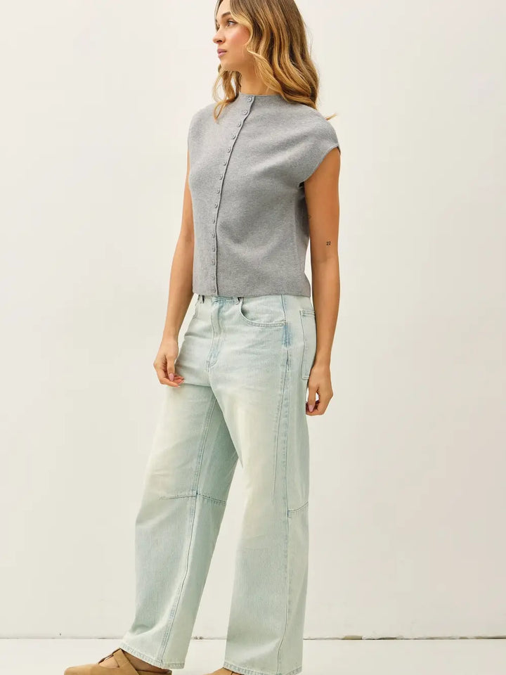 Woman wearing a gray top and light blue jeans against a white background