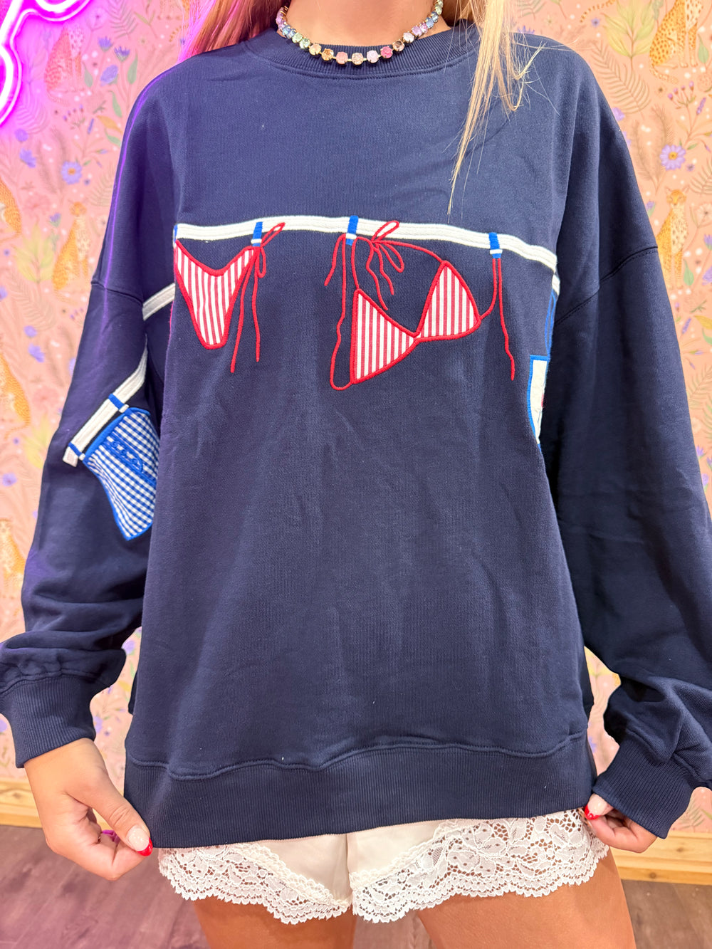 Navy blue sweatshirt with red bikini design worn by a person.