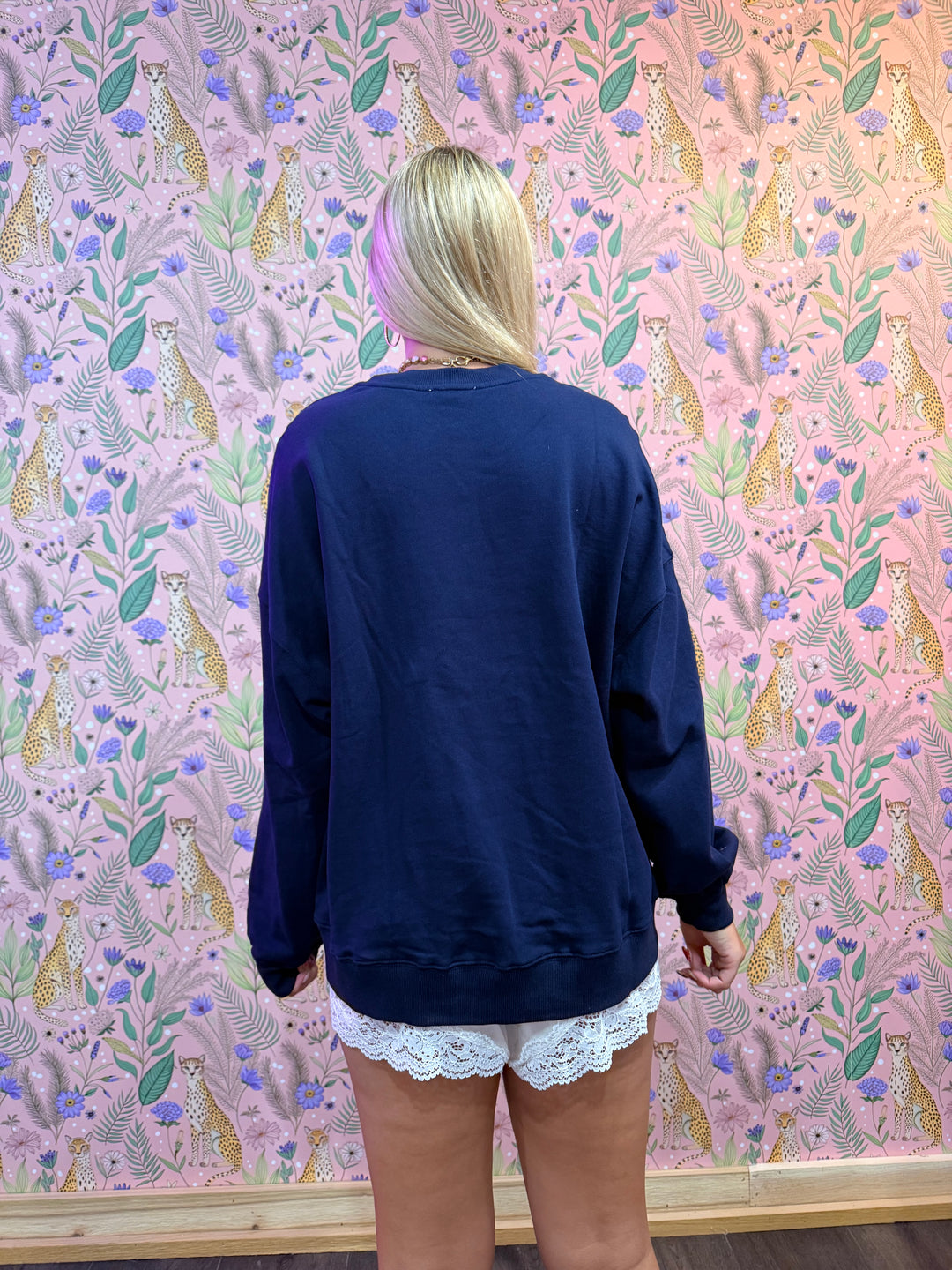 Person wearing a navy blue outfit with white lace trim on a patterned pink background