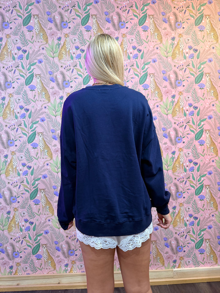 Person wearing a navy blue outfit with white lace trim on a patterned pink background