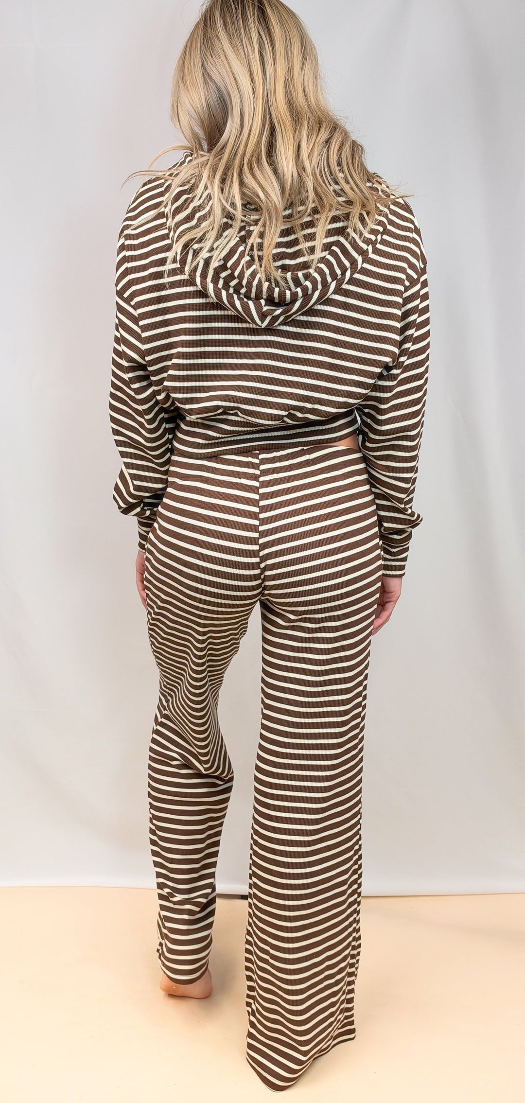 Woman shown from back wearing matching brown and white stripe set on plain background