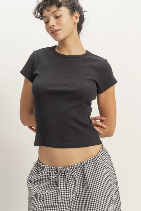 Woman wearing a black t-shirt and checkered pants on a plain background