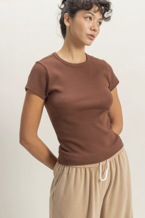 Woman wearing a brown short-sleeve top and beige pants on a white background