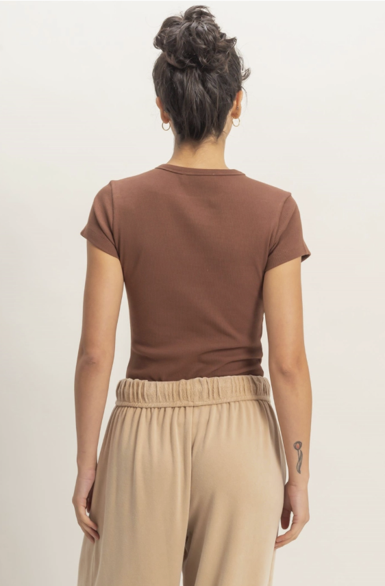 Person wearing a brown t-shirt and beige pants on a plain background