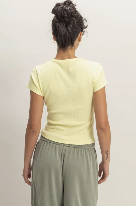 Woman wearing a light green top and olive green pants against a plain background