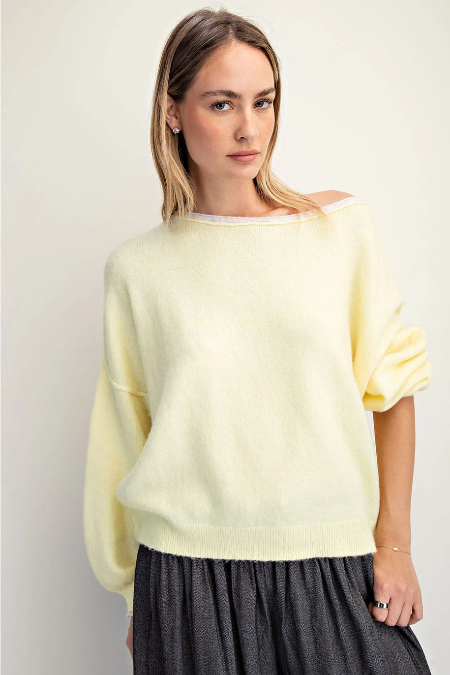 Woman wearing a light yellow sweater against a plain background
