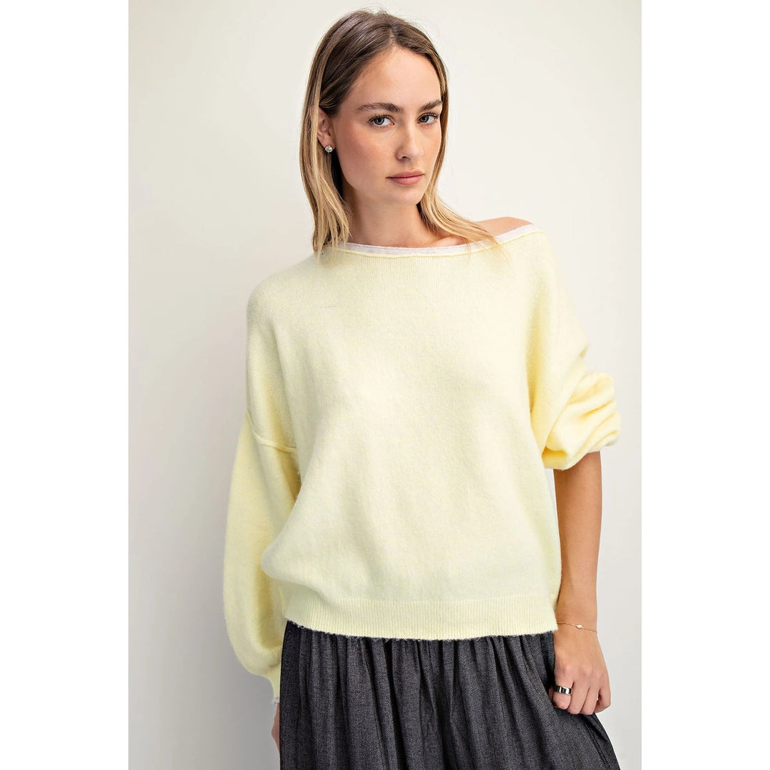 Woman wearing a light yellow sweater against a plain background