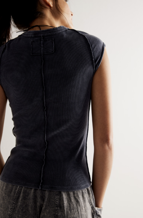Person wearing a black sleeveless top with a plain background