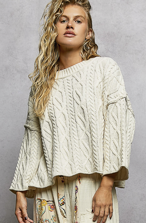 Woman wearing cream knit sweater on plain background