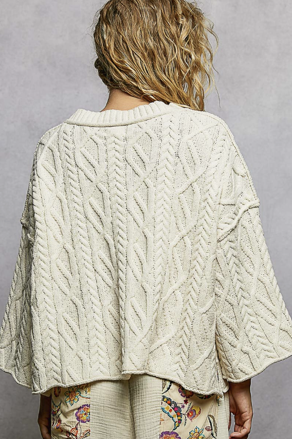 Woman wearing cream knit pullover on plain background