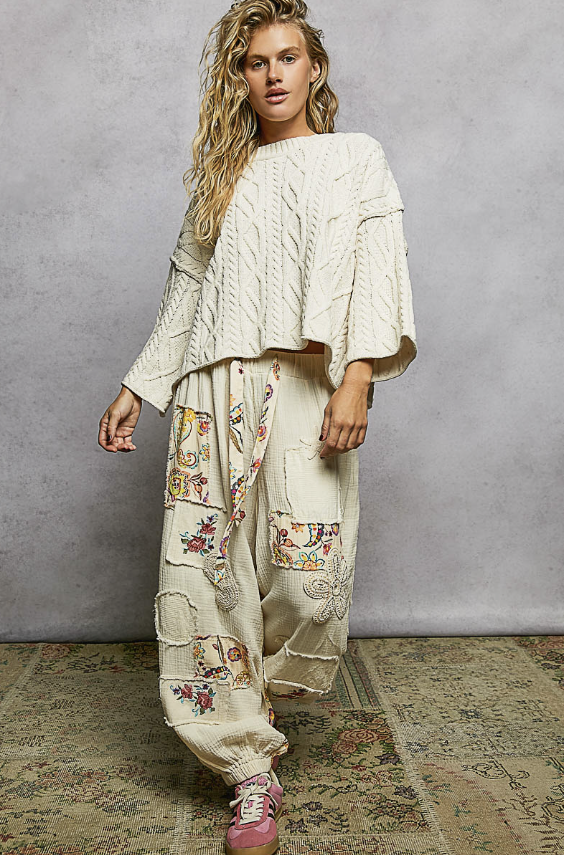 Woman wearing cream knit pullover on plain background