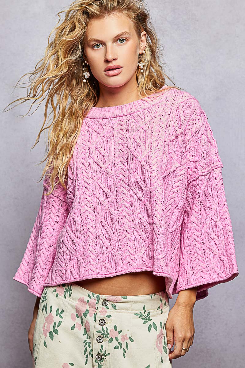 woman wearing pink sweater on plain background