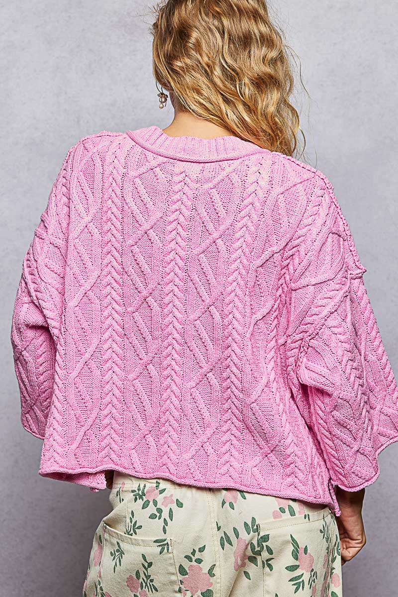 woman wearing pink sweater on plain background