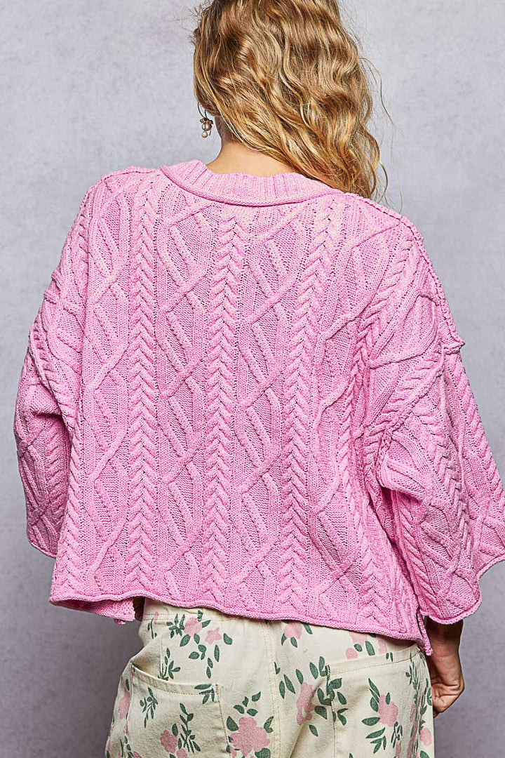 woman wearing pink sweater on plain background
