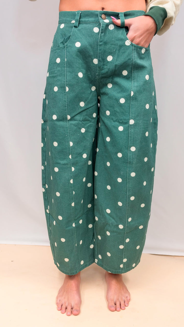 Woman wearing green polka dot barrel jeans on plain background