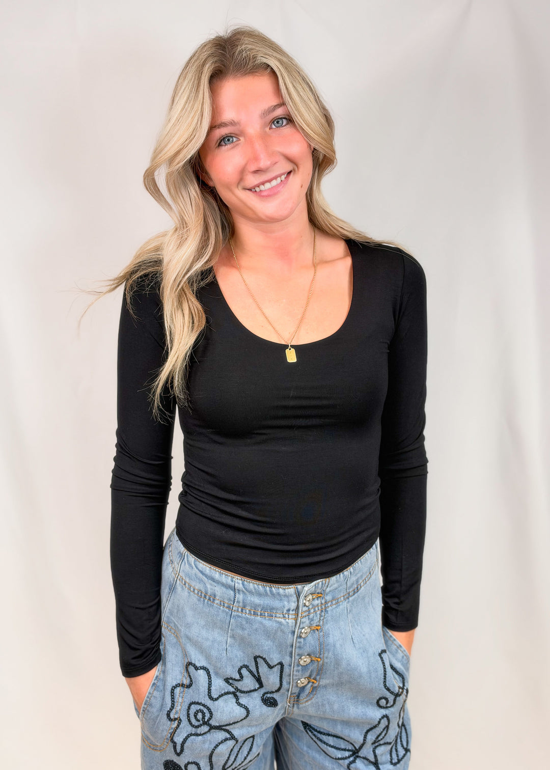 Woman wearing black long sleeve shirt on plain background