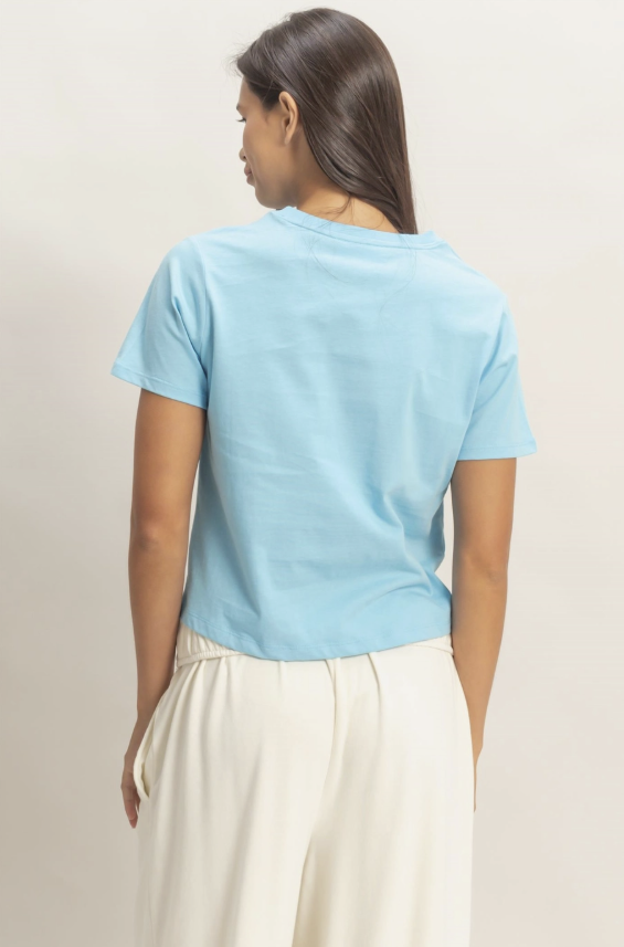 Person wearing a light blue t-shirt and white pants on a plain background