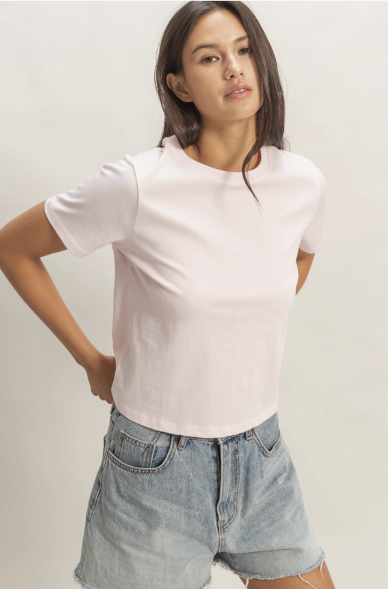 Woman wearing a white t-shirt and denim shorts against a plain background