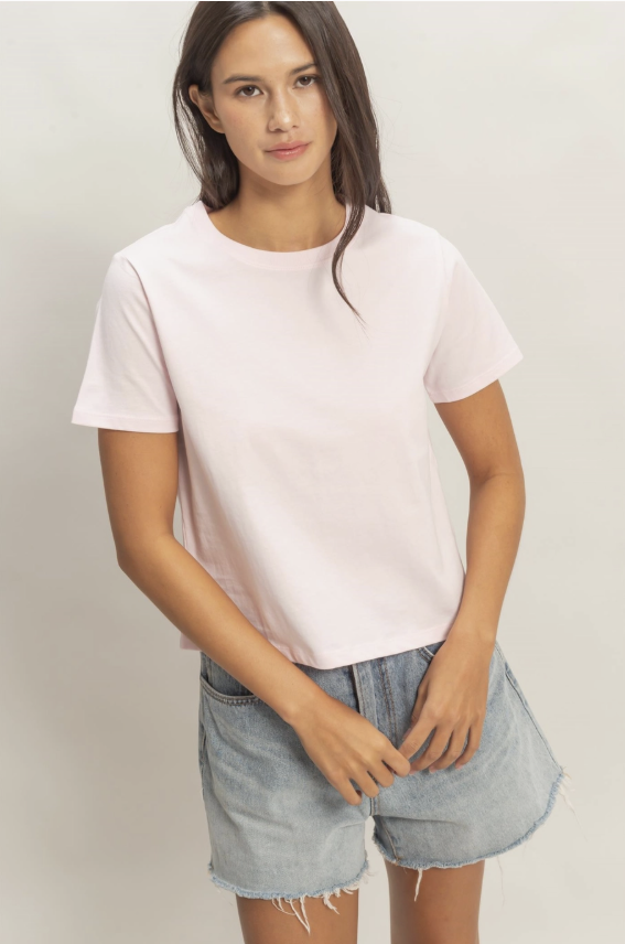 Woman wearing a white t-shirt and denim shorts on a plain background