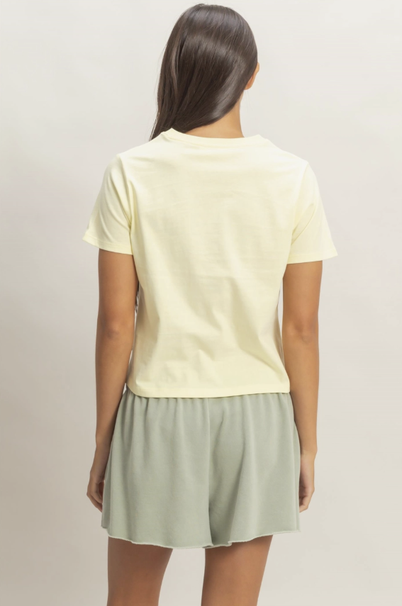 Person wearing a light yellow t-shirt and light green shorts on a plain background