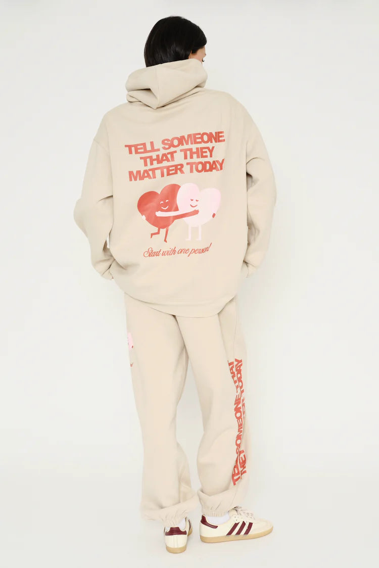 Person wearing a beige tracksuit with red text and graphics on a white background