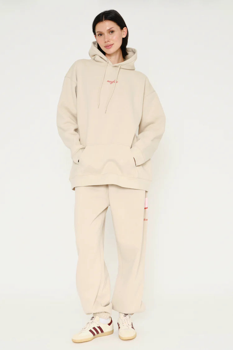 Person wearing a beige tracksuit with Adidas shoes on a white background