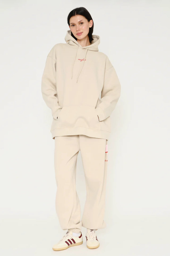 Person wearing a beige tracksuit with Adidas shoes on a white background