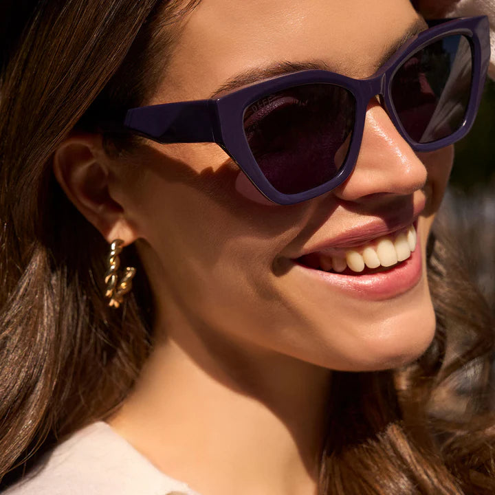 Woman wearing purple sunglasses with a blurred background