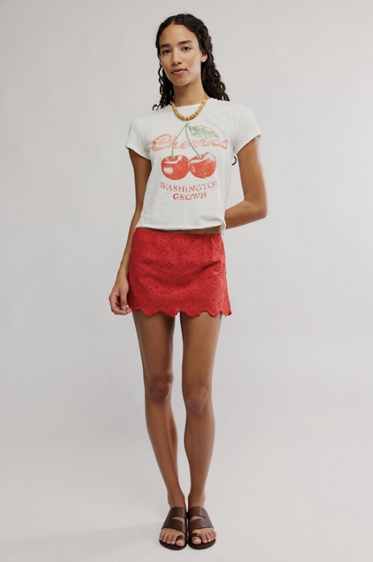 Woman wearing a white t-shirt with red graphics and a red skirt on a plain background