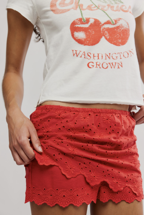 Person wearing a white t-shirt with cherries and &