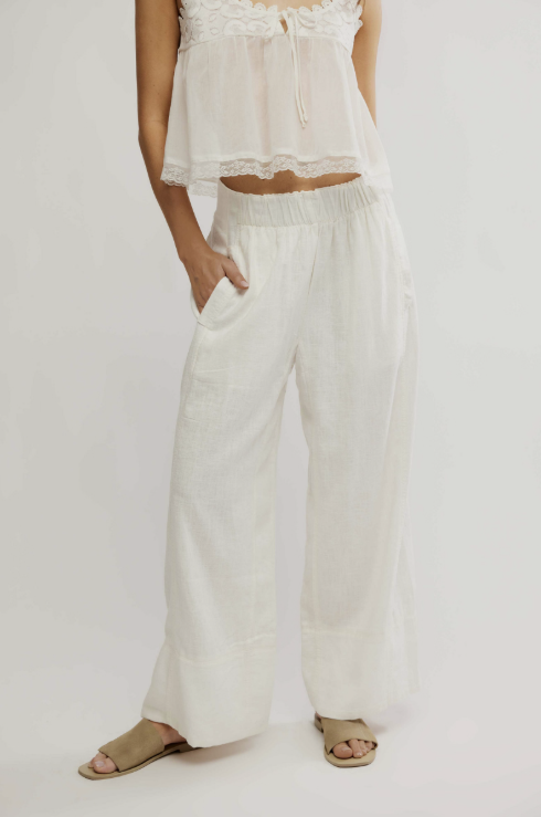 Person wearing a white outfit with wide-leg pants on a plain background