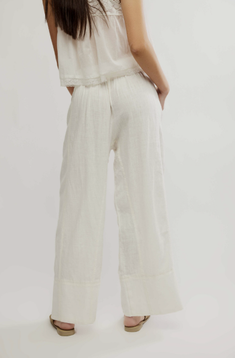 Person wearing a white outfit with wide-leg pants on a plain background