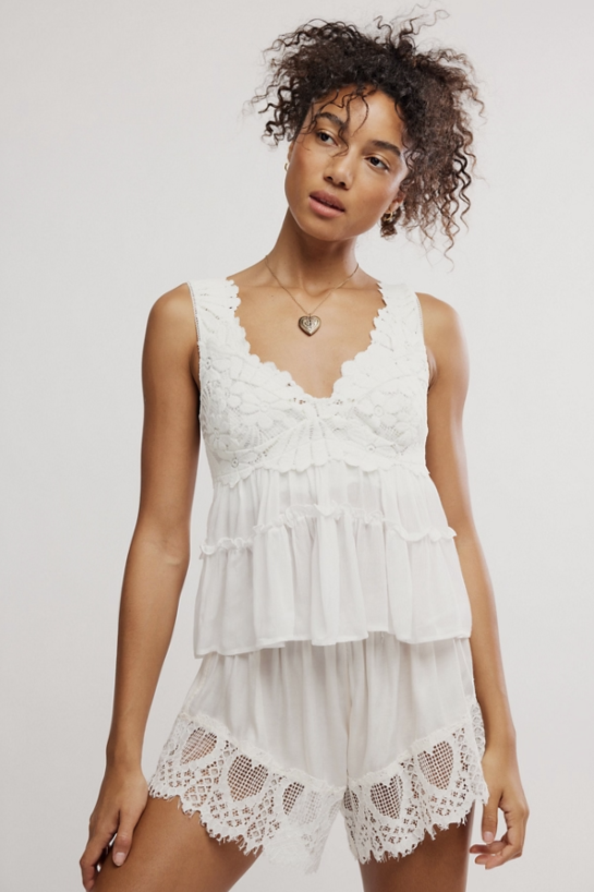 Woman wearing lace cami and shorts on plain background