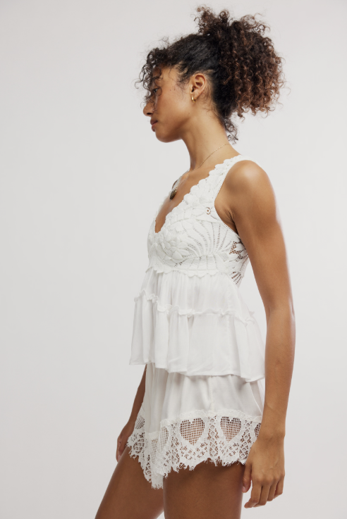 Woman wearing white lace cami on plain background