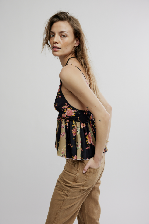 Woman wearing a floral top and beige pants against a plain background