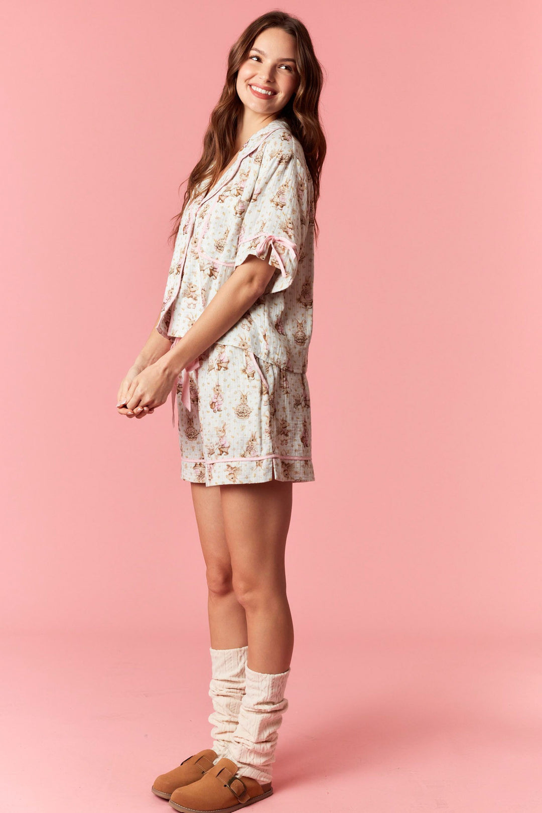 Woman wearing a floral dress and slippers on a pink background