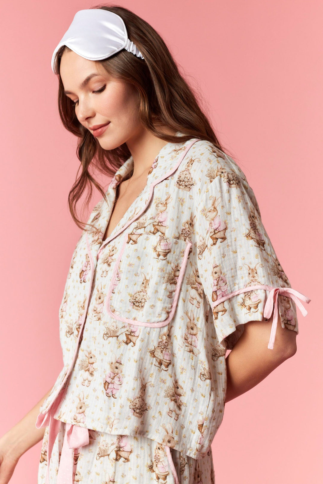 Woman wearing a floral pajama set with a matching headband on a pink background