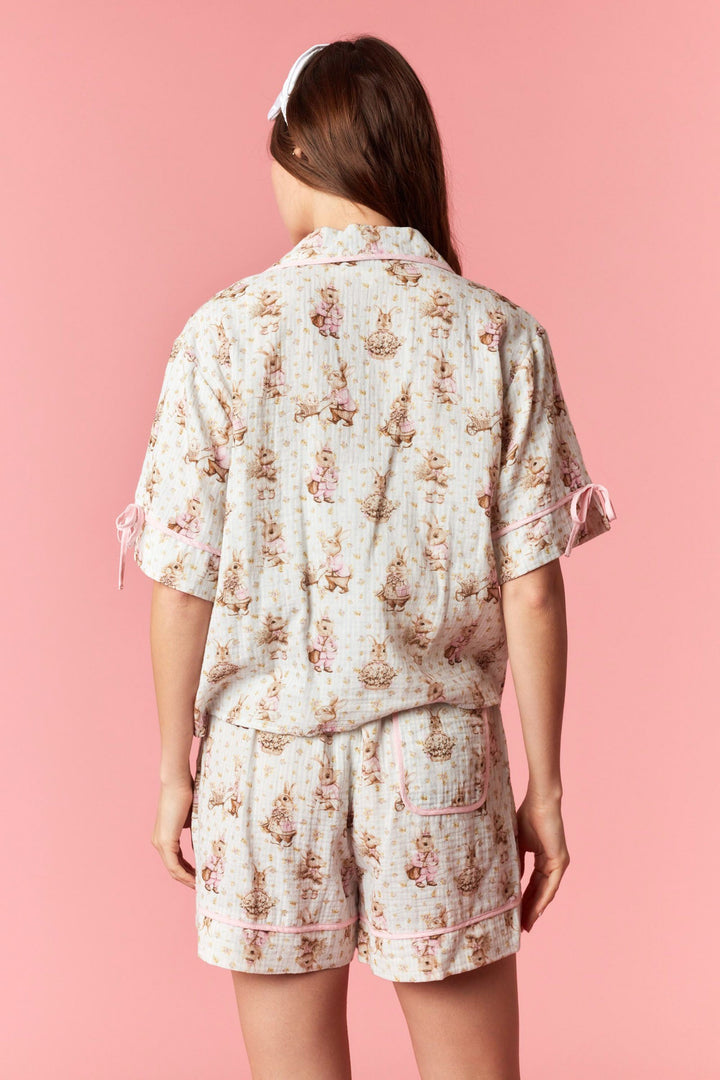Person wearing a floral pajama set against a pink background