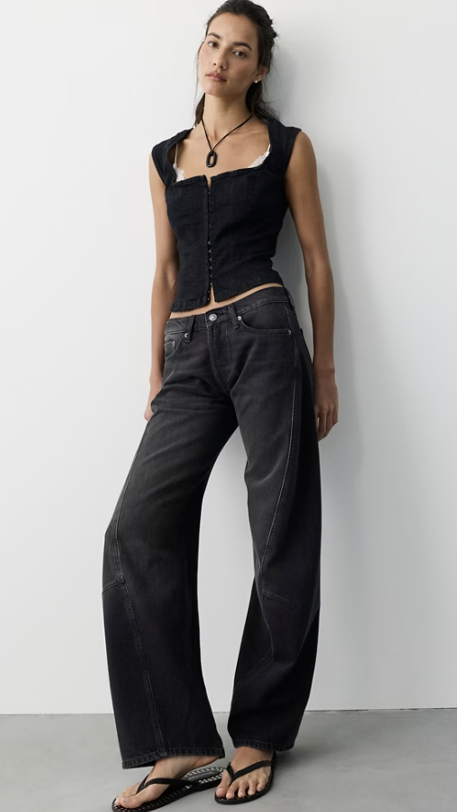 Woman wearing black tank and black jeans on plain background