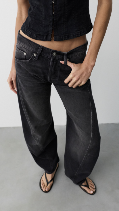 Close up of woman wearing black tank and black jeans on plain background