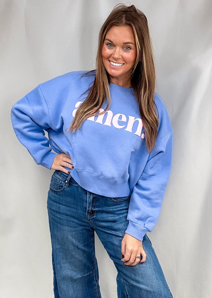 A woman modeling a light blue crewneck sweatshirt with white text that reads &