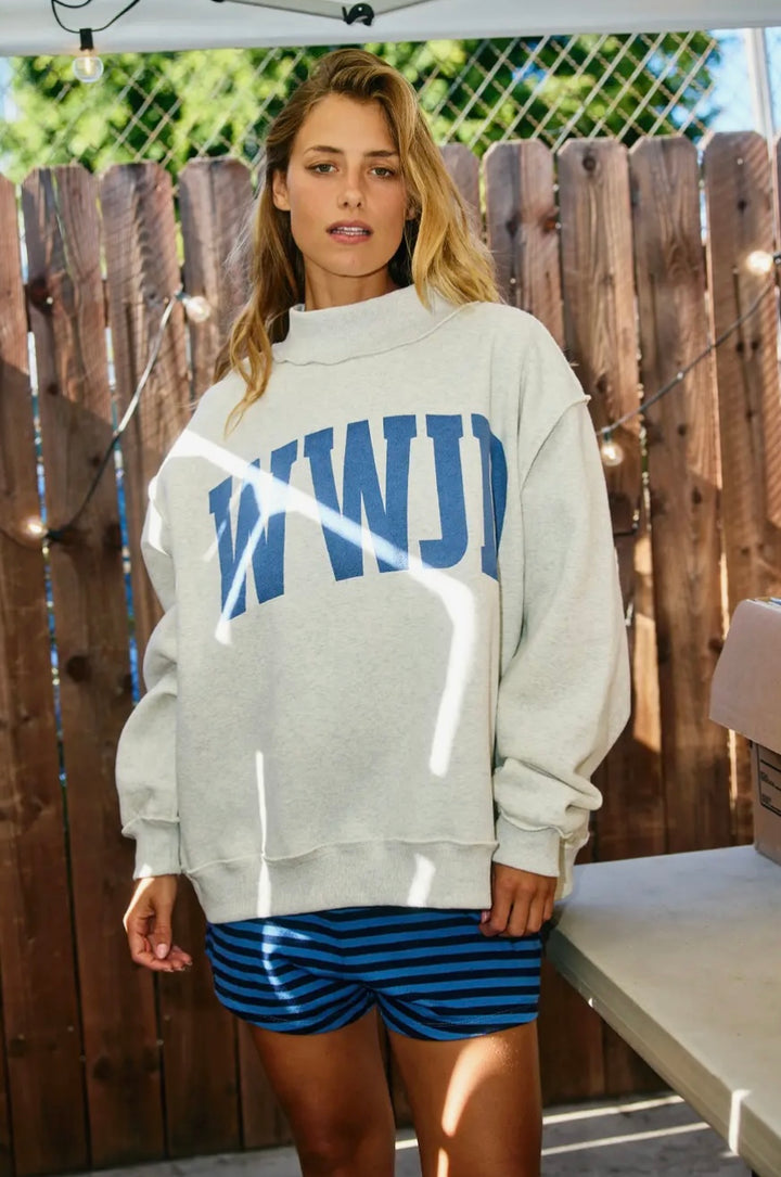 Woman wearing grey sweatshirt and striped shorts outdoors