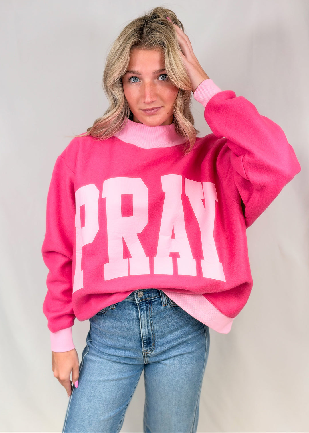 Woman wearing pink mock neck sweatshirt with &