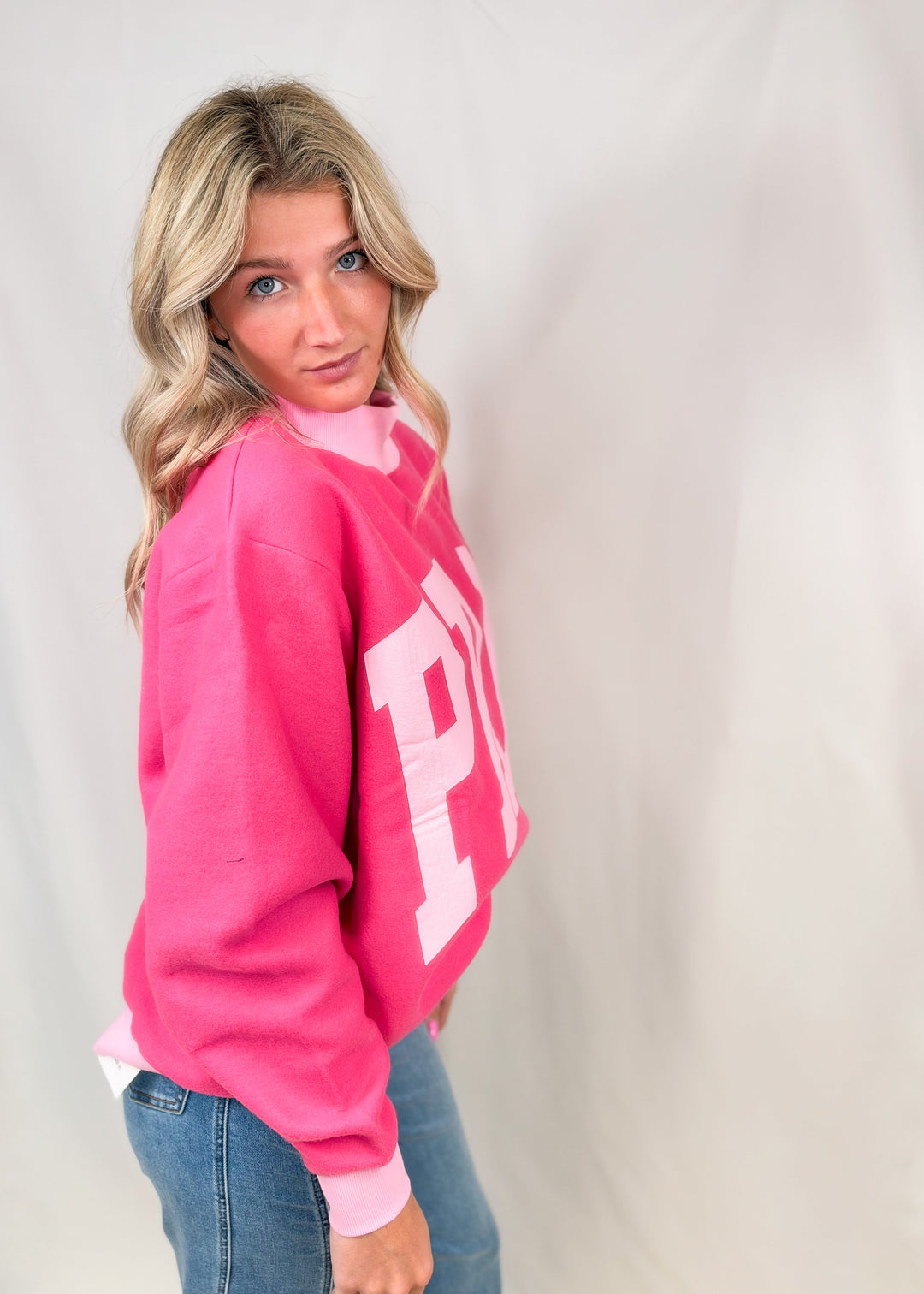 Woman wearing pink mock neck sweatshirt with &