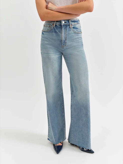Person wearing light blue flared jeans on a white background