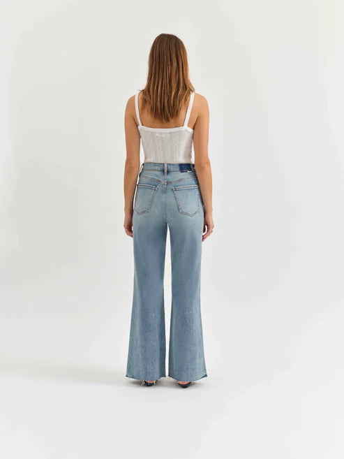 Woman wearing light blue jeans and a white top on a white background