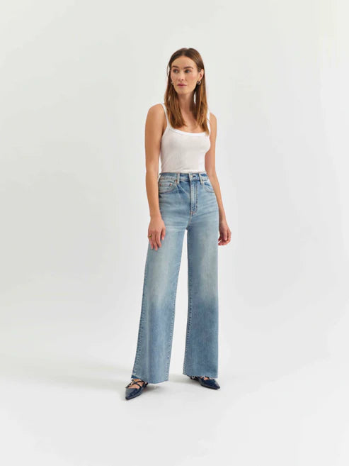 Woman wearing a white tank top and light blue jeans on a white background