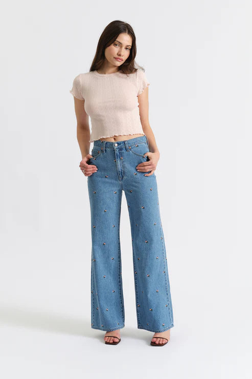 Woman wearing a beige top and blue jeans on a white background