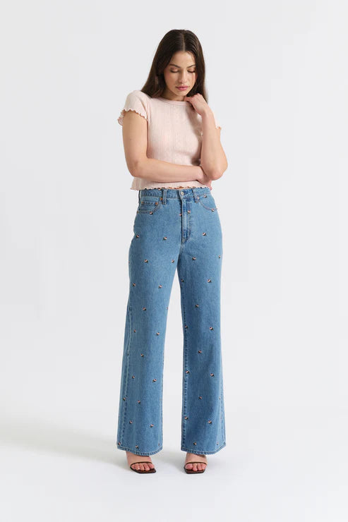Woman wearing light blue jeans and a pink top on a white background